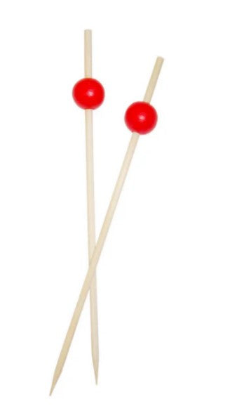 A bamboo pick with a round red ball at the top, adding a vibrant and stylish touch to appetizers or cocktails.