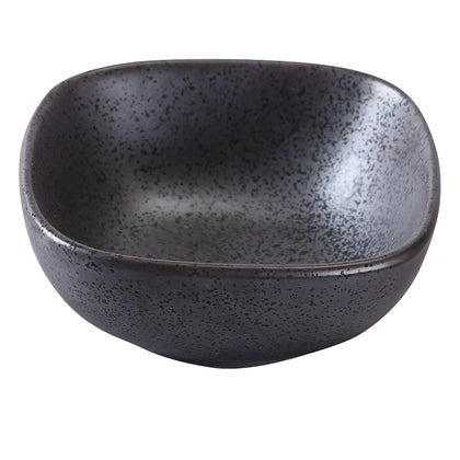 This square porcelain bowl features a matte black finish and reactive glaze that enhances any dish. Its compact size and shape add modern elegance to both casual and upscale table settings such as restaurants, cafes, and home dining. High quality and affordable restaurant dinnerware.